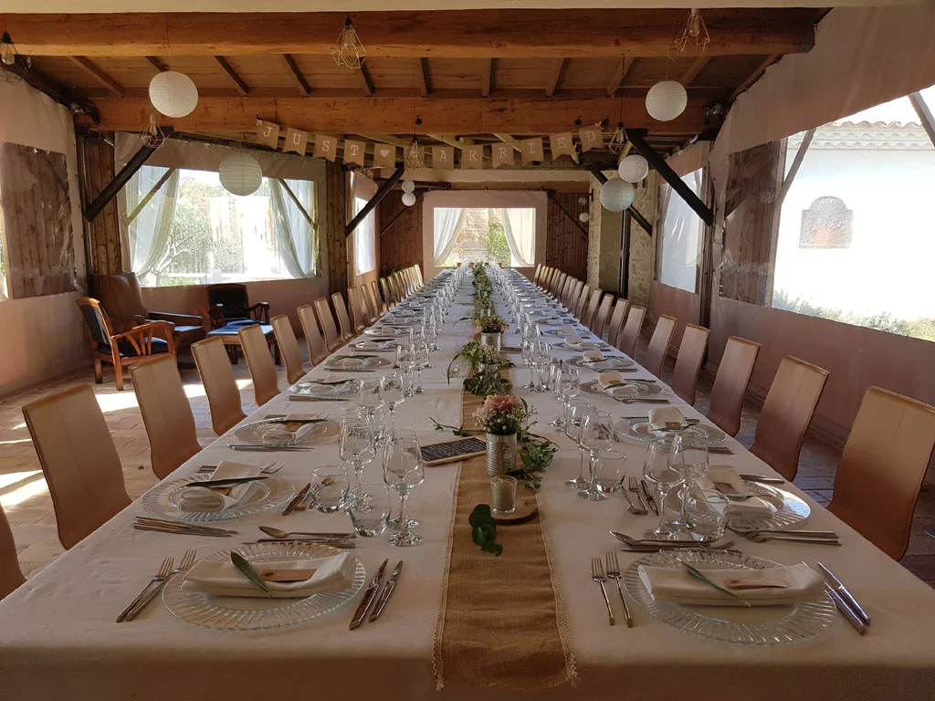 Une grande table dressée sous la terrasse couverte du Mas