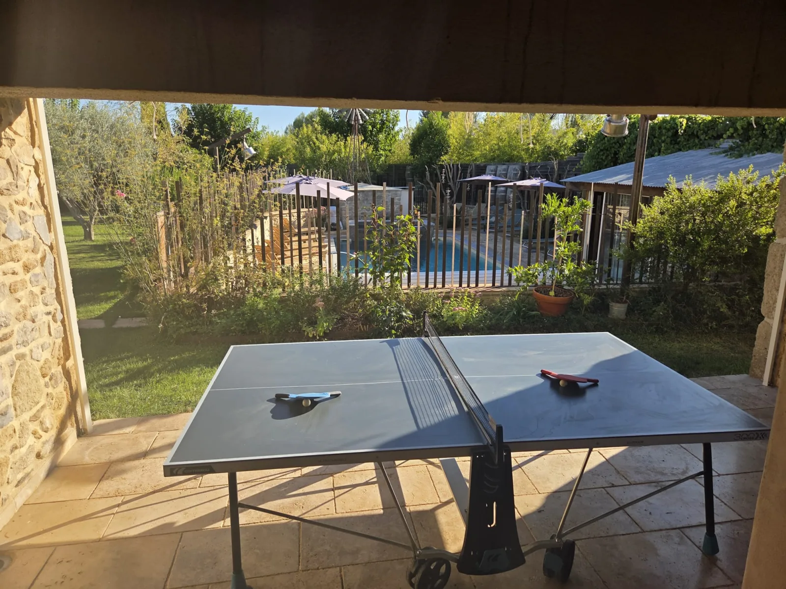 La table de ping-pong sur la terrasse, face au jardin et à la piscine